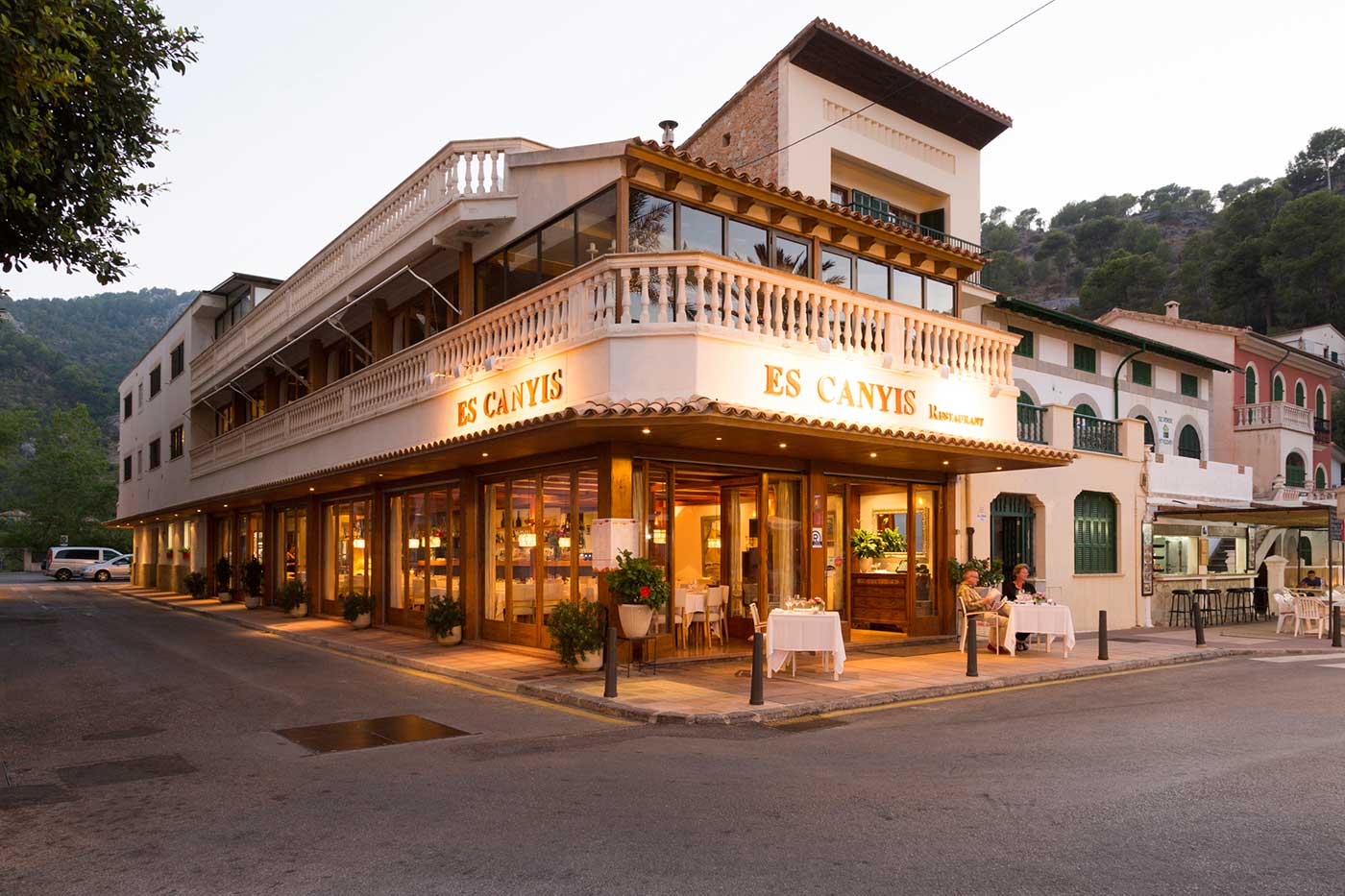 Restaurant Es Canyís in Port de Sóller bij schemering, met verlichte ramen en de berghelling erachter