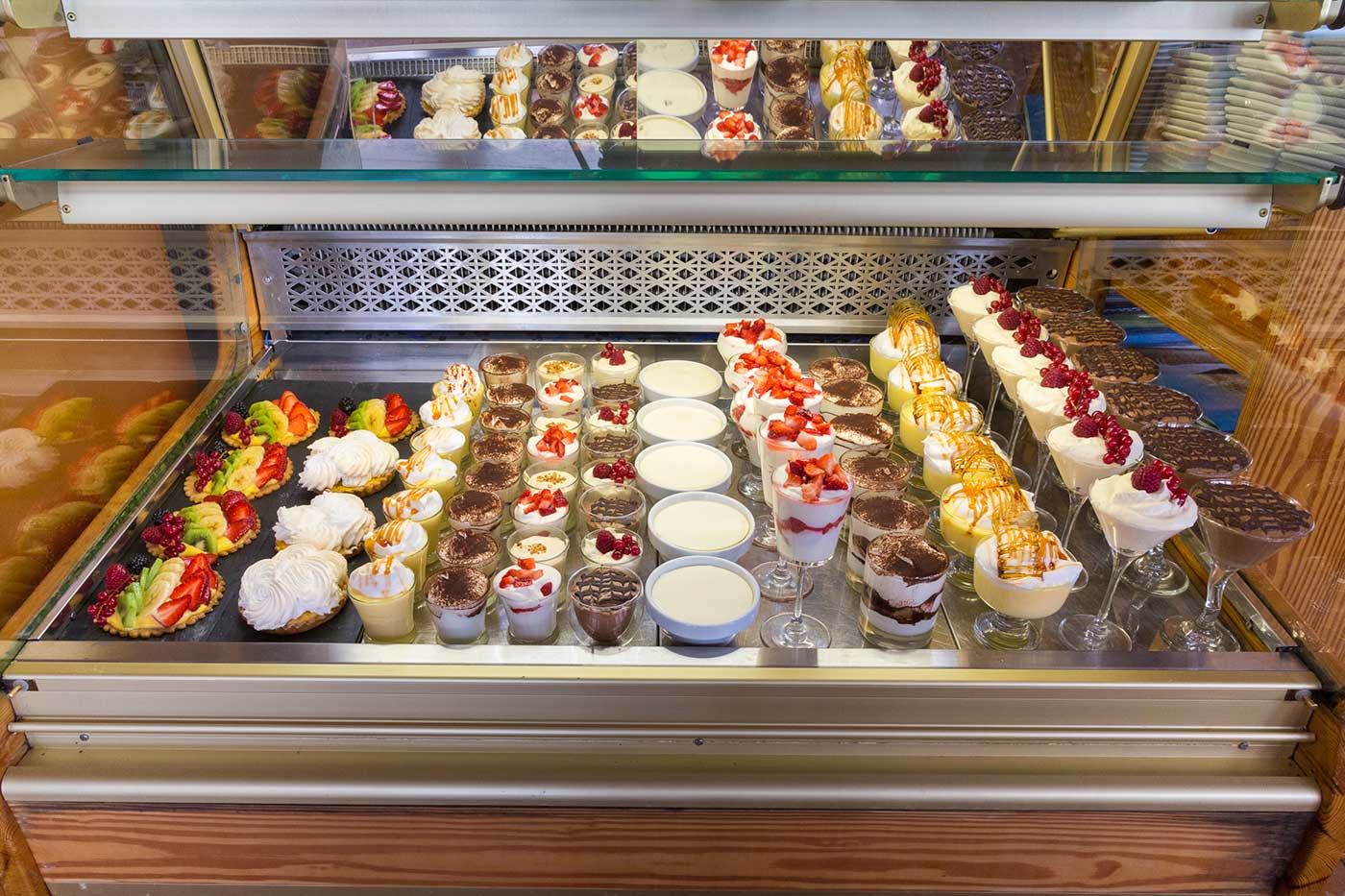 De dessertvitrine van Es Canyís met rijen taartjes, mousses en glazen nagerechten achter glas
