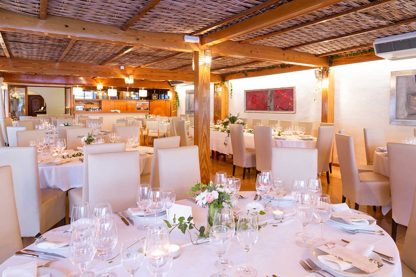 De benedenzaal van Es Canyís met wit gedekte tafels, witte stoelhoezen en een houten lattenplafond