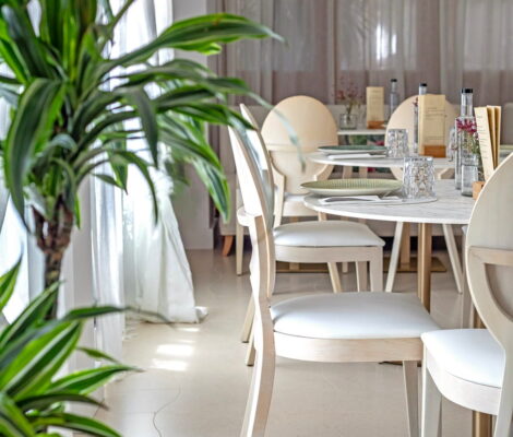 De lichte eetzaal van Es Marès op Formentera met ronde marmeren tafels, lichthouten stoelen en ijle gordijnen