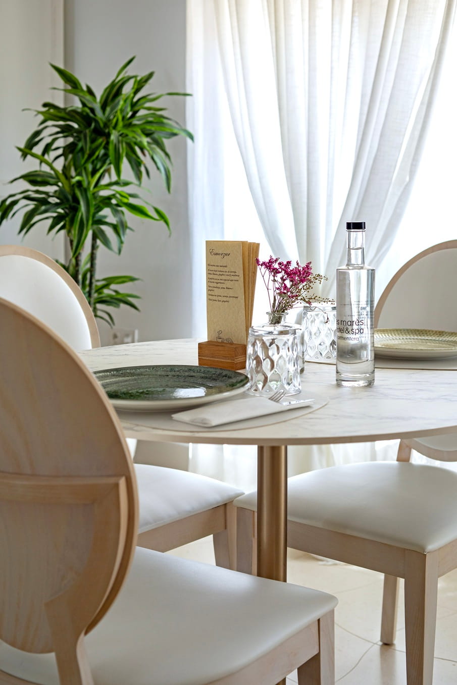 Gedekte tafel bij Es Marès met een groen bord, een karaf water van het huis en droogbloemen