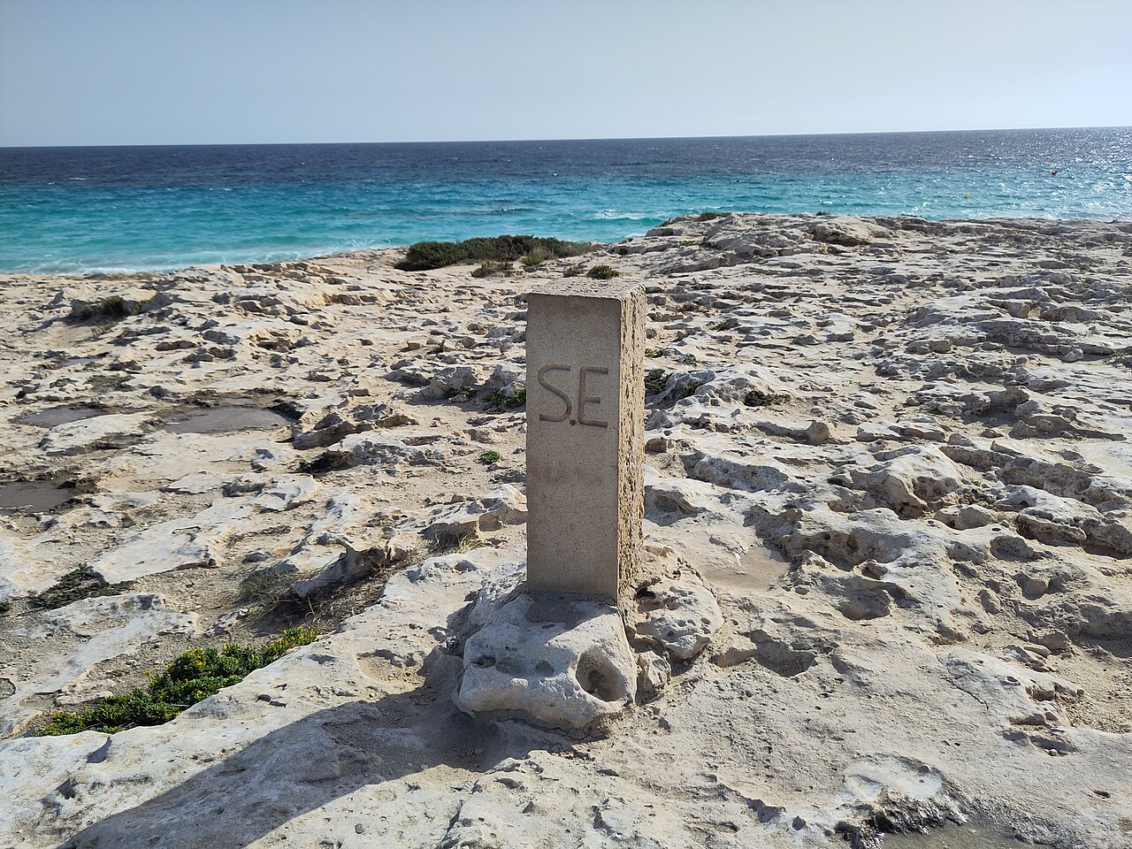Es Trucadors Formentera: de landtong met zee aan twee kanten 7 Stenen grenspaal met de letters S.E. op de rotsen van Es Trucadors, met de zee op de achtergrond