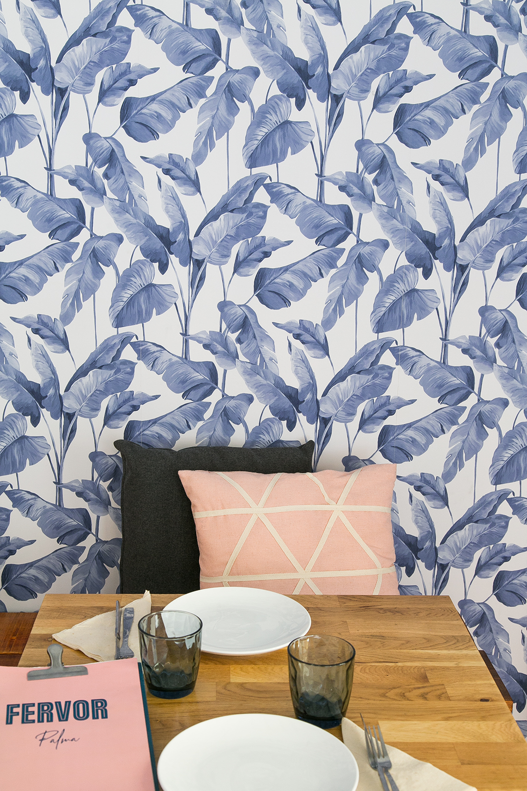Fervor Palma: eten in een oude kantine uit 1890 8 Gedekte houten tafel bij Fervor in Palma met de menukaart van het huis, tegen een wand met blauw bladerbehang