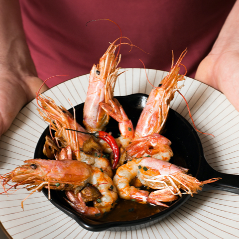 Fervor Palma: eten in een oude kantine uit 1890 4 Zwarte pan met gegrilde garnalen en rode peper, in de handen van een ober bij Fervor in Palma