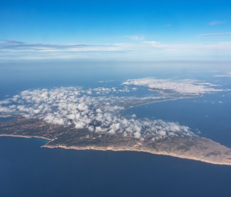 Formentera vanuit een vliegtuig gezien in april, met stapelwolken boven het eiland en de landtong Es Trucadors op de achtergrond