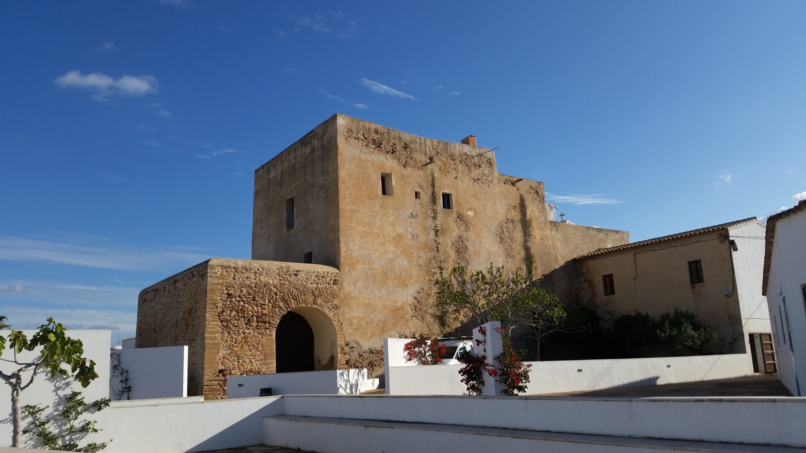 De witte vestingkerk van Sant Francesc Xavier op Formentera, gezien van achteren onder een decemberlucht