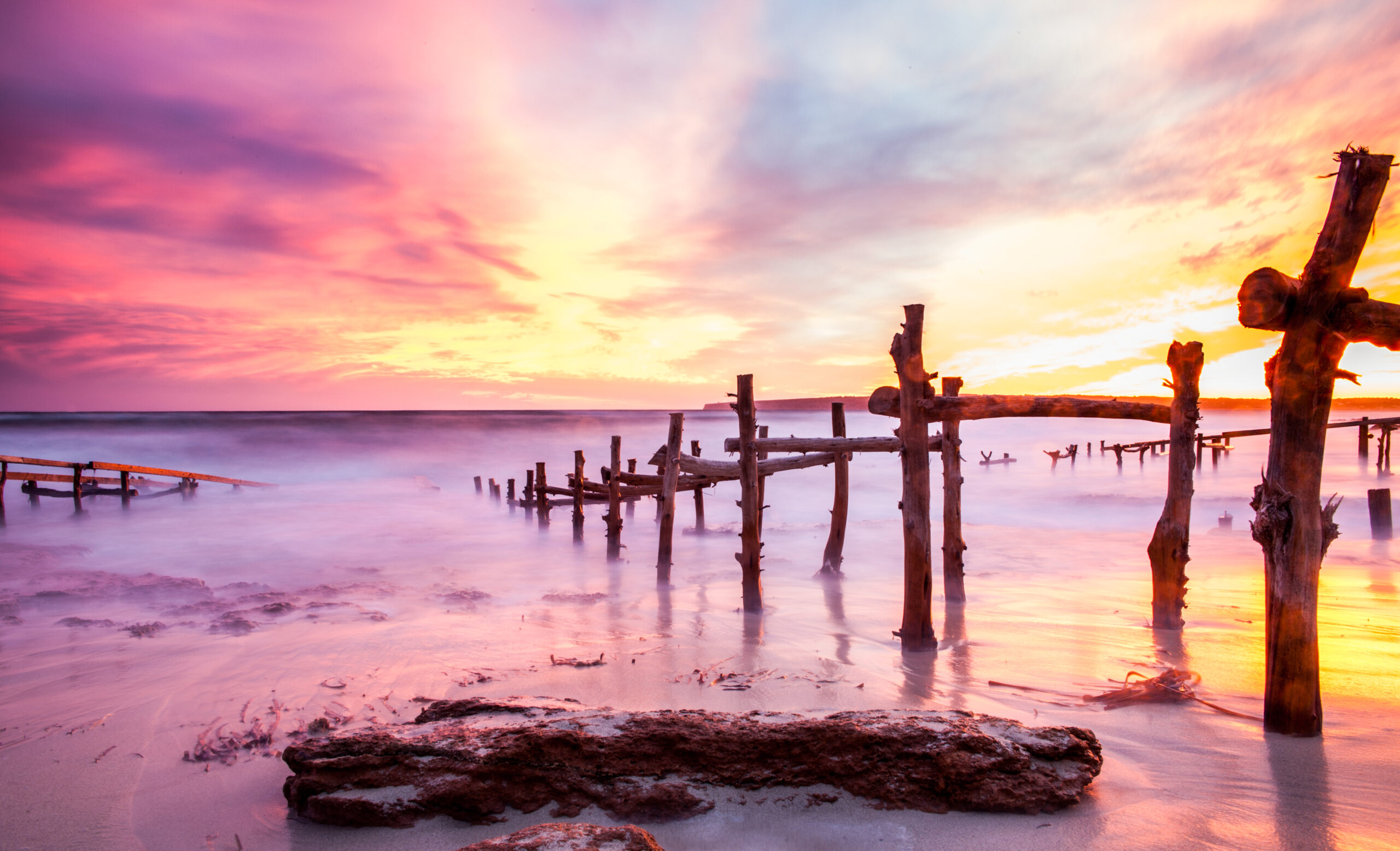 Formentera in september: het warmste zeewater en een leger eiland 1 Roze en gele zonsondergang boven de oude houten bootsteigers aan de kust van Formentera