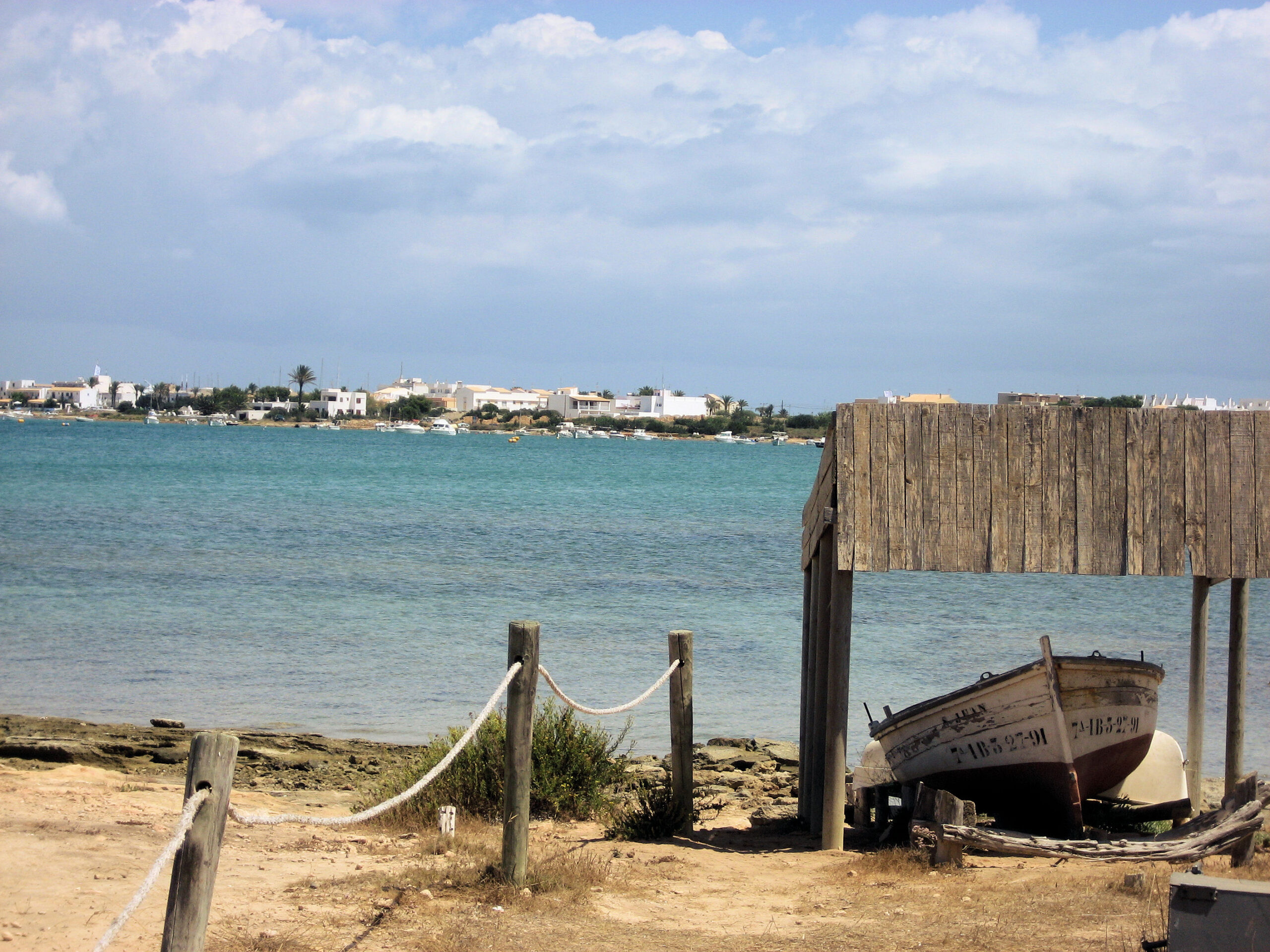 Formentera met kinderen: ondiep water, de boot en wat er niet is 1 De vlakke lagune Estany des Peix op Formentera, met de haven van La Savina op de achtergrond