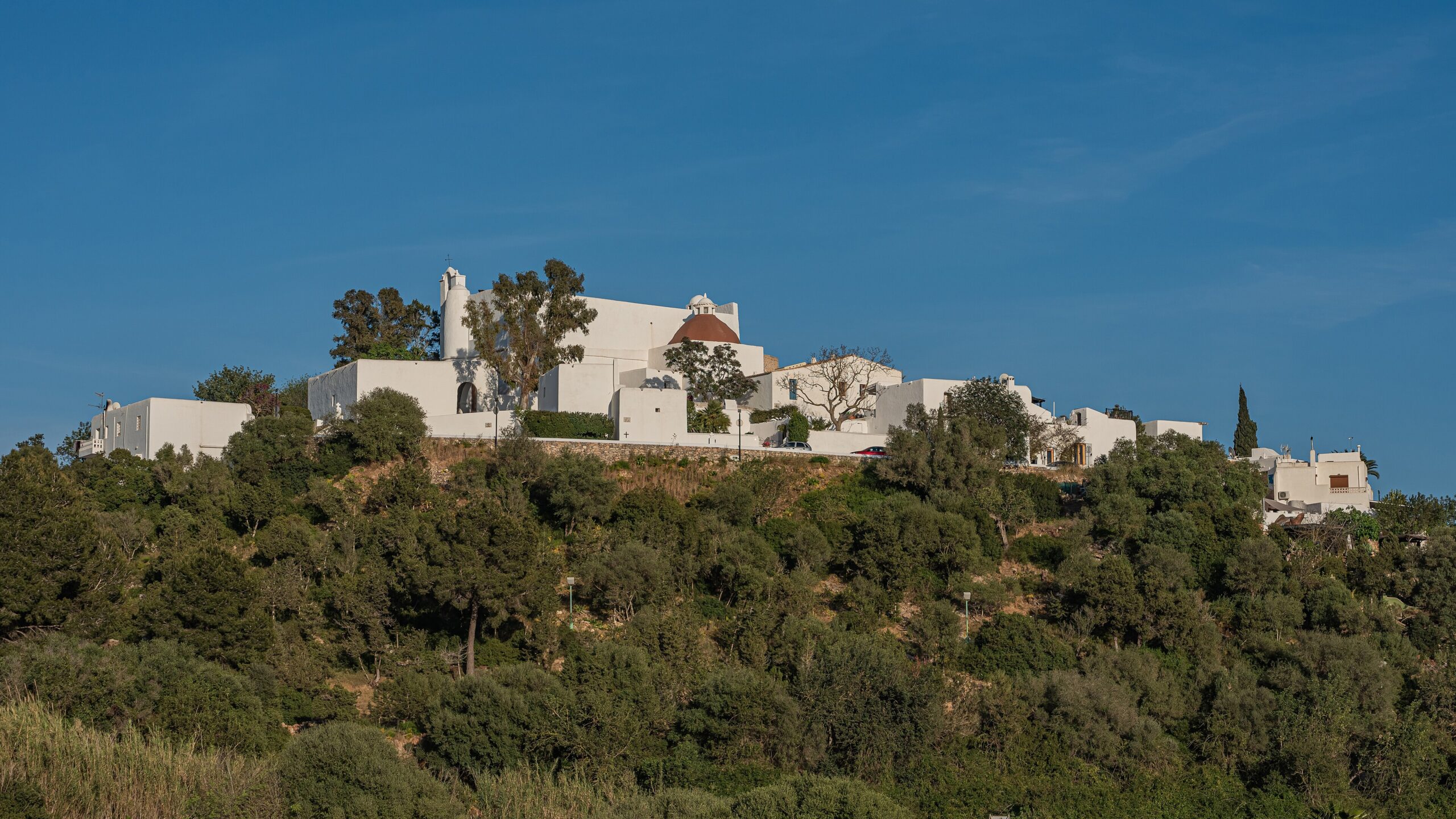 De witte kerkheuvel Puig de Missa boven Santa Eulària des Riu op Ibiza, met groene begroeiing in april