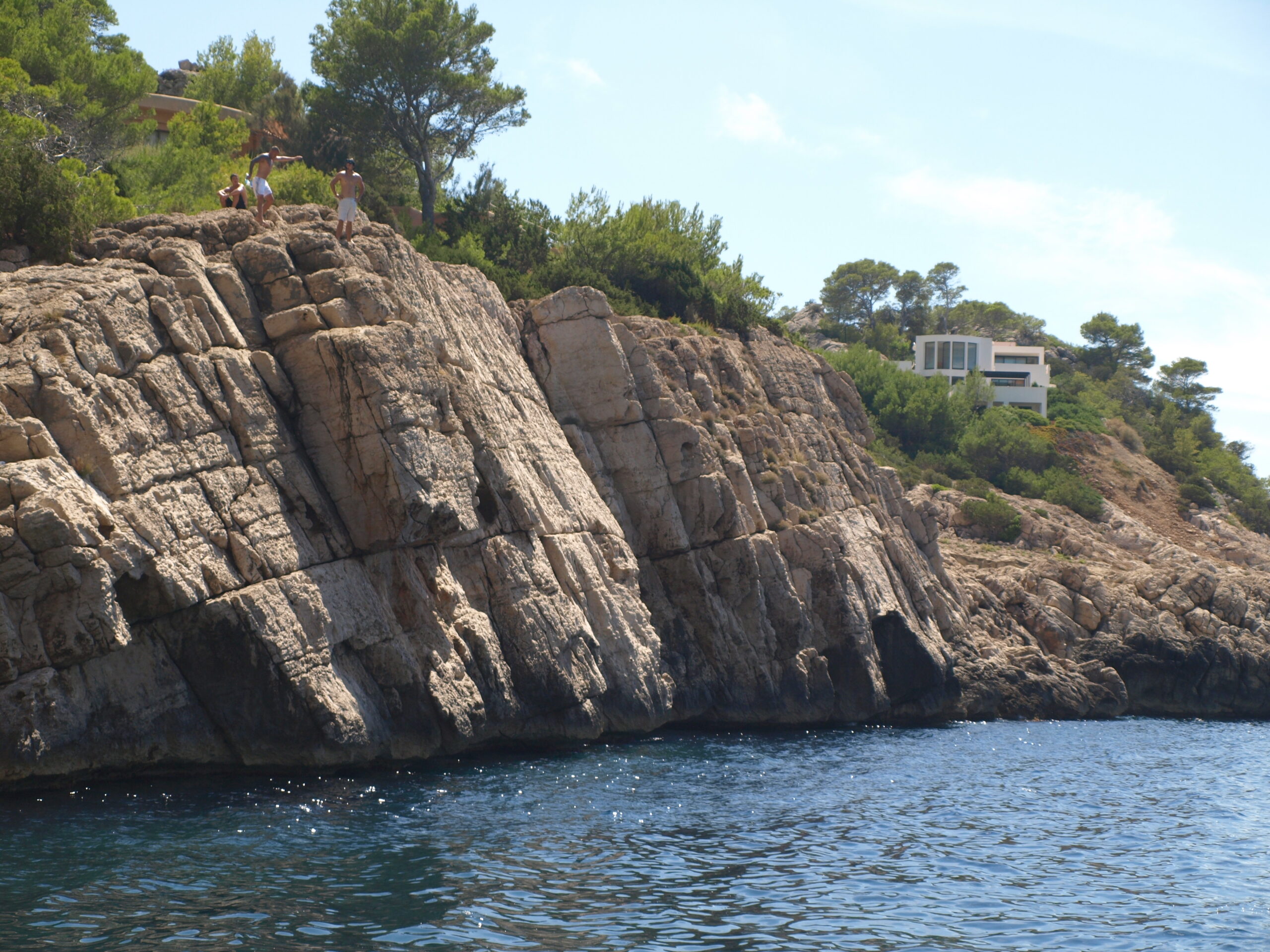 Het strand van Cala Salada op Ibiza met badgasten en helder turquoise water eind augustus