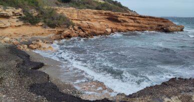 Leeg strandje bij de Canal de l'Olla op Ibiza met branding en een grijze winterlucht