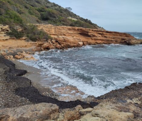 Leeg strandje bij de Canal de l'Olla op Ibiza met branding en een grijze winterlucht