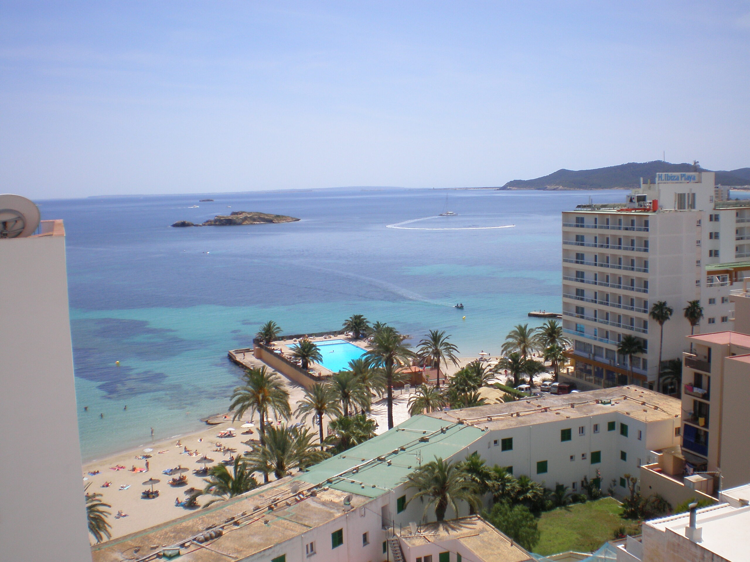 Ibiza in juni: weer, zeewater en de vuren van Sant Joan 2 Het stadsstrand van ses Figueretes in Ibiza-stad met ligbedden, palmen en helder water in juni