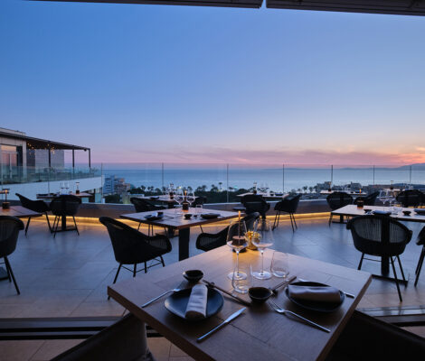 Het dakterras van restaurant KATAGI Blau aan de Playa de Palma bij zonsondergang, met gedekte tafels en uitzicht over de baai van Palma
