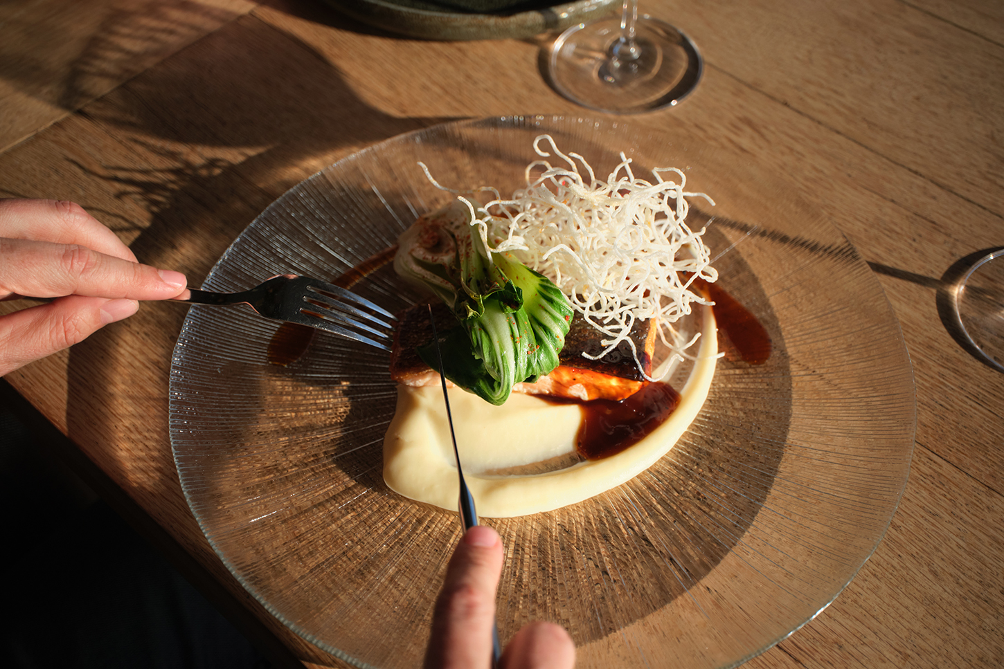 Hoofdgerecht van KATAGI Blau met vis, paksoi, knapperige rijstnoedels en aardappelpuree op een glazen bord