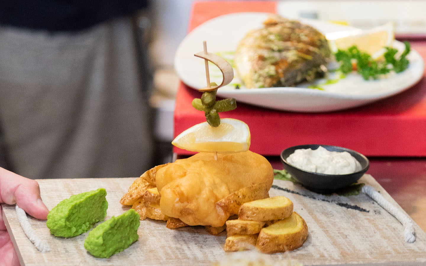 Kingfisher Port de Sóller: vis en zeevruchten boven de jachthaven 4 Fish and chips van Kingfisher op een houten plank, met doperwtenpuree, een bakje saus en een partje citroen op een prikkertje