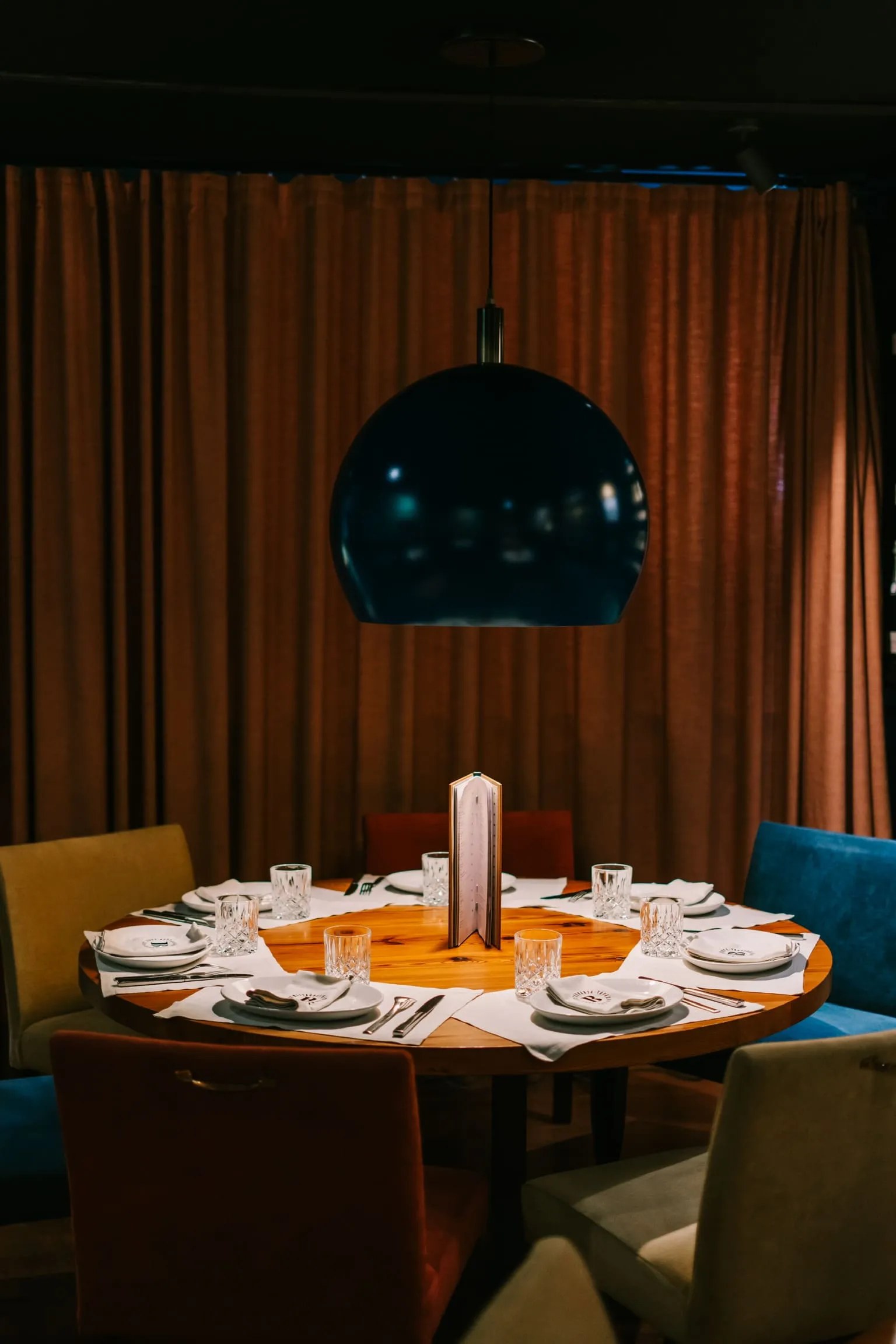 Ronde tafel met gekleurde stoelen in een aparte zaal van La Bodeguilla in Palma, achter een zwaar gordijn
