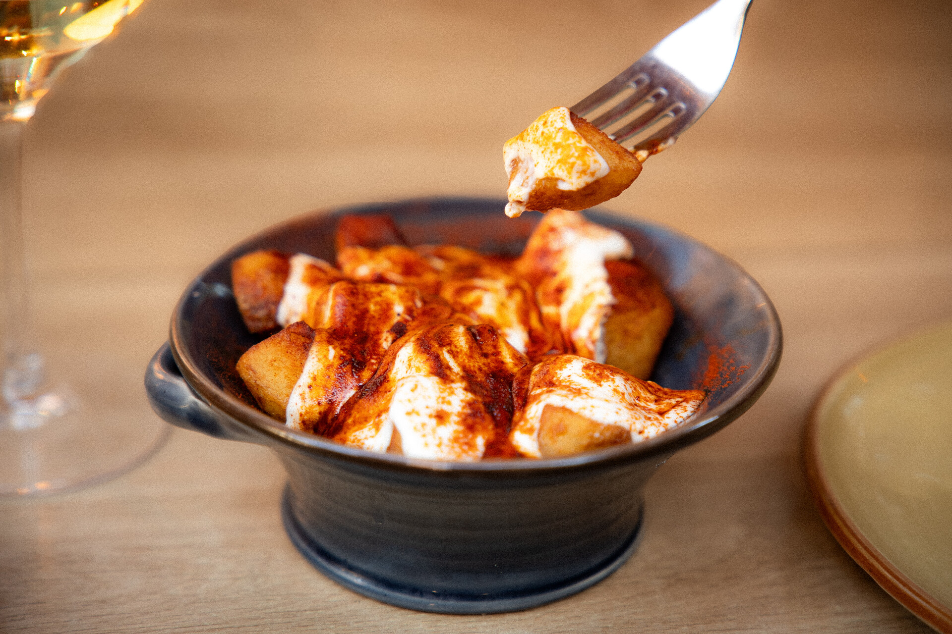 Patatas bravas met pittige saus en alioli in een donkere aardewerken kom bij La Malvasia in Palma