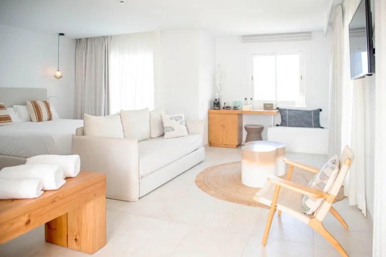 Las Mimosas Ibiza: boutiquehotel met zeventien suites bij Sant Antoni 2 Suite van Las Mimosas Ibiza met witte bank, bed en licht hout