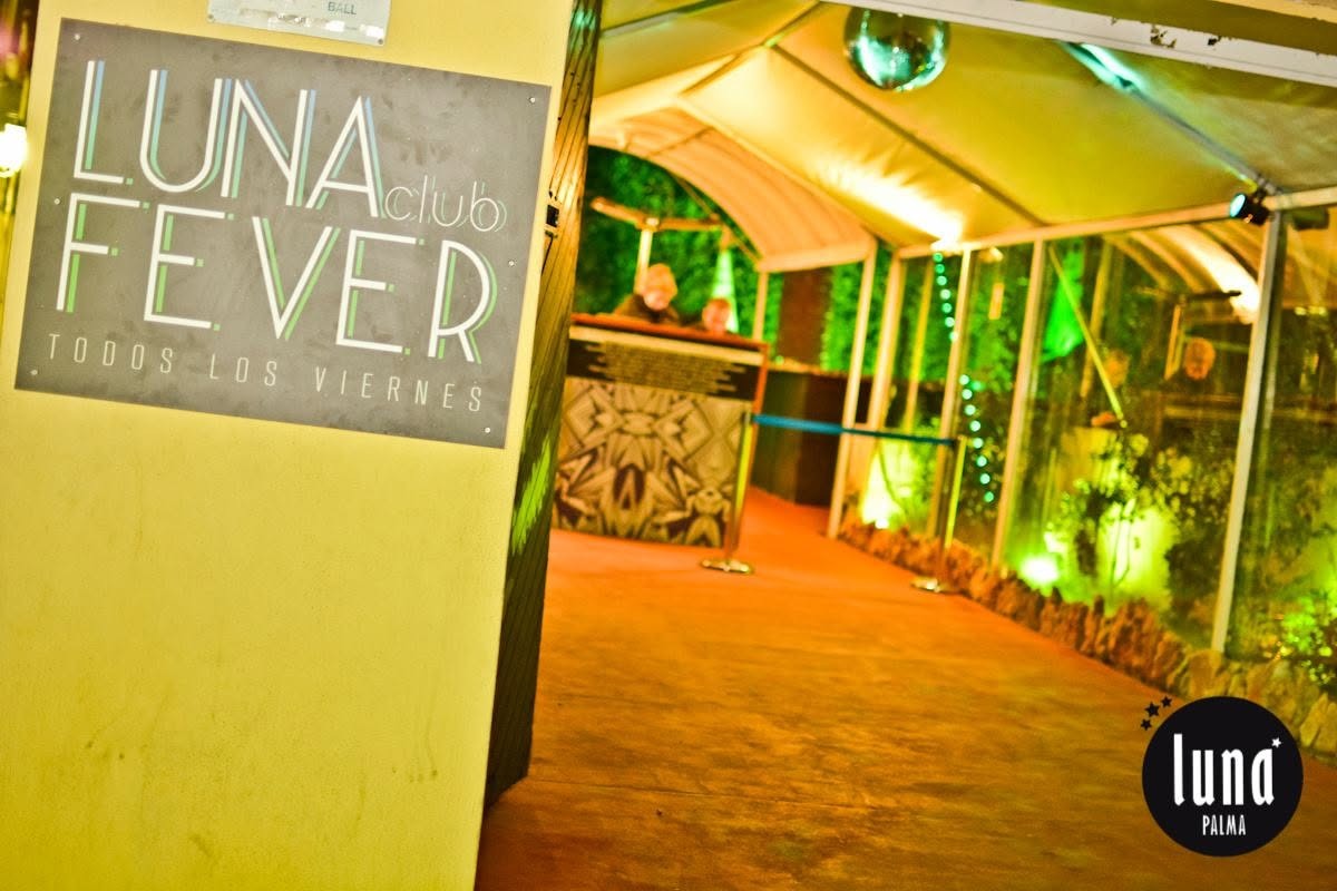 De overdekte doorgang naar de patio van Luna Palma met een verlicht bord van de club