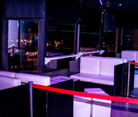 De VIP-hoek van Luna Palma met witte banken en paarse verlichting, en de lichten van de baai van Palma door het raam