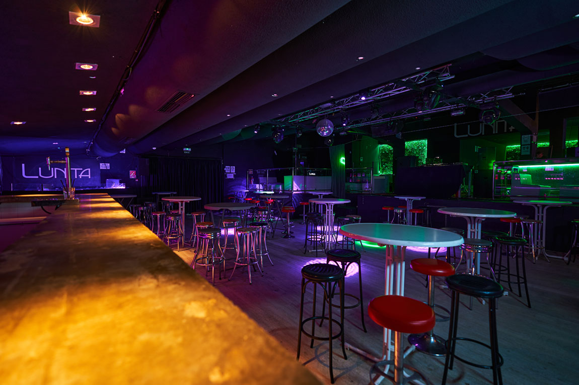 Lunita Can Pastilla: de technoclub met zwembad bij Playa de Palma 5 De lange verlichte bar van Lunita in Can Pastilla met statafels en groen licht in de zaal
