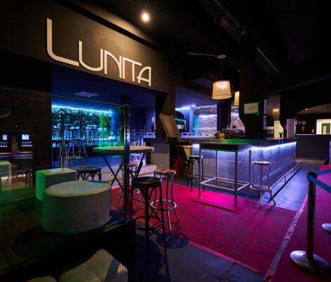 De bar van club Lunita in Can Pastilla met het verlichte logo boven de tap en roze vloerverlichting