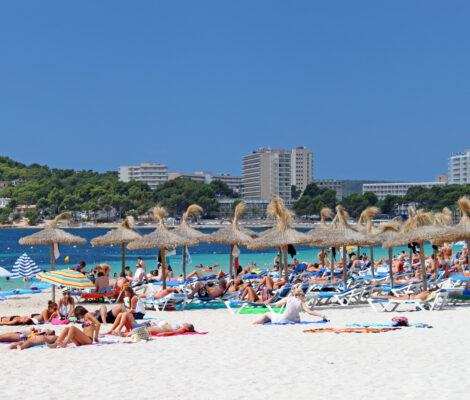 Het strand van Magaluf op Mallorca met badgasten, parasols en turquoise water op een julidag