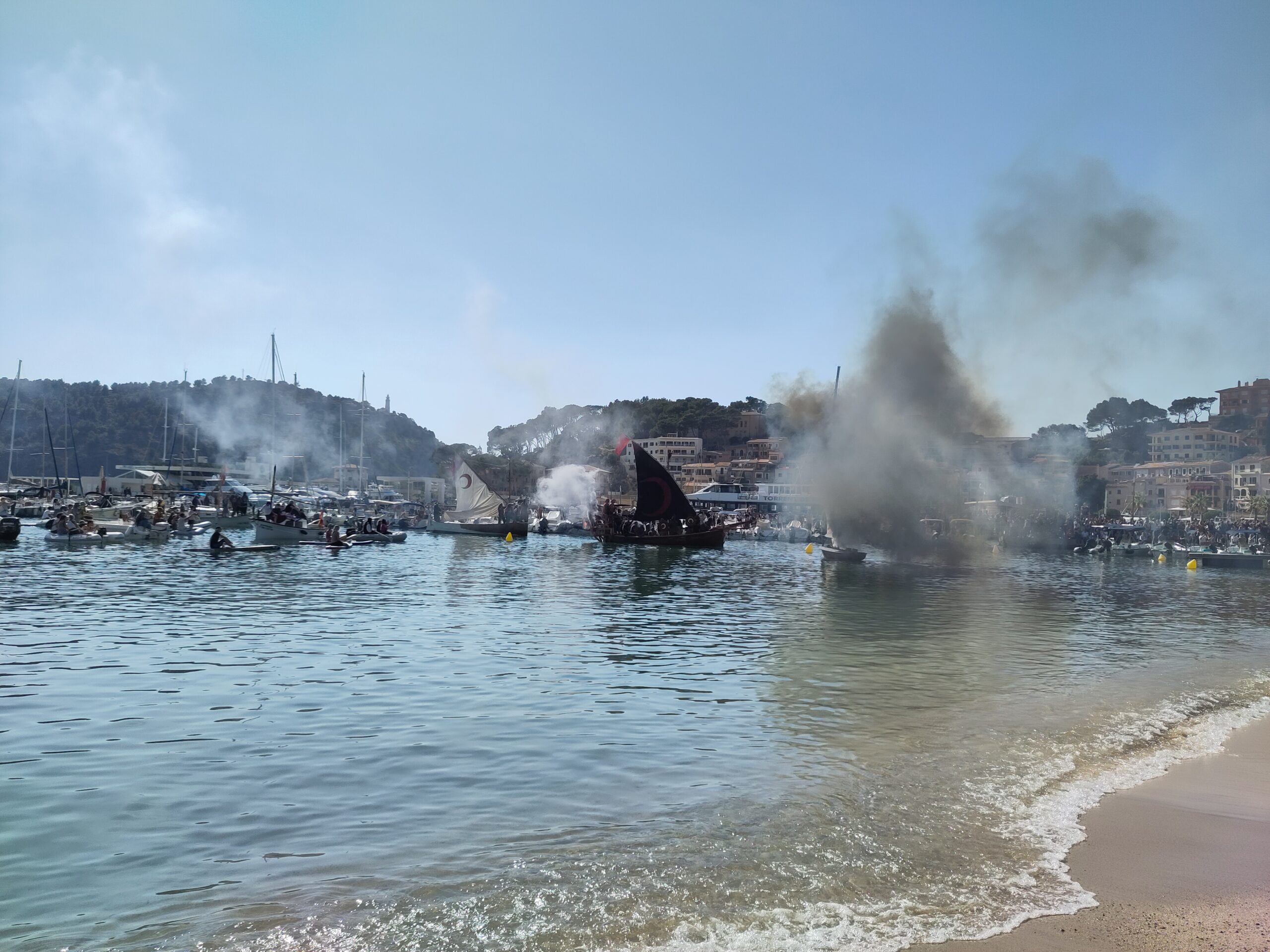 Boten met moros varen onder kanonrook de baai van Port de Sóller binnen tijdens Es Firó