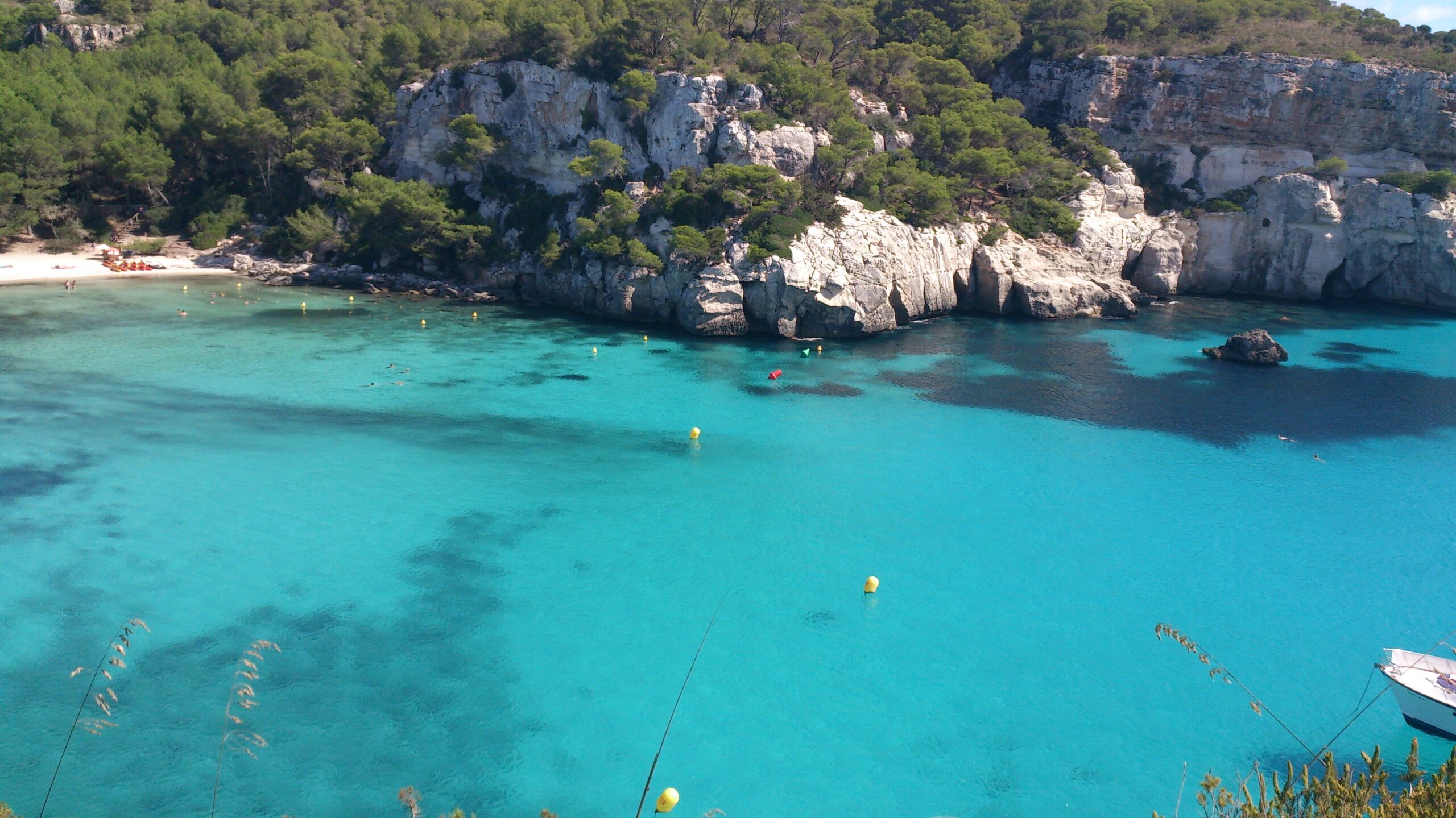 Menorca in september: warm water en de festes van Gràcia 1 Turquoise water van Cala Macarella op Menorca met een vrijwel leeg strand en witte kliffen in september