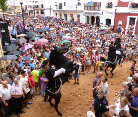 Vol plein in Maó met twee steigerende zwarte paarden tijdens het jaleo van de festes de Gràcia
