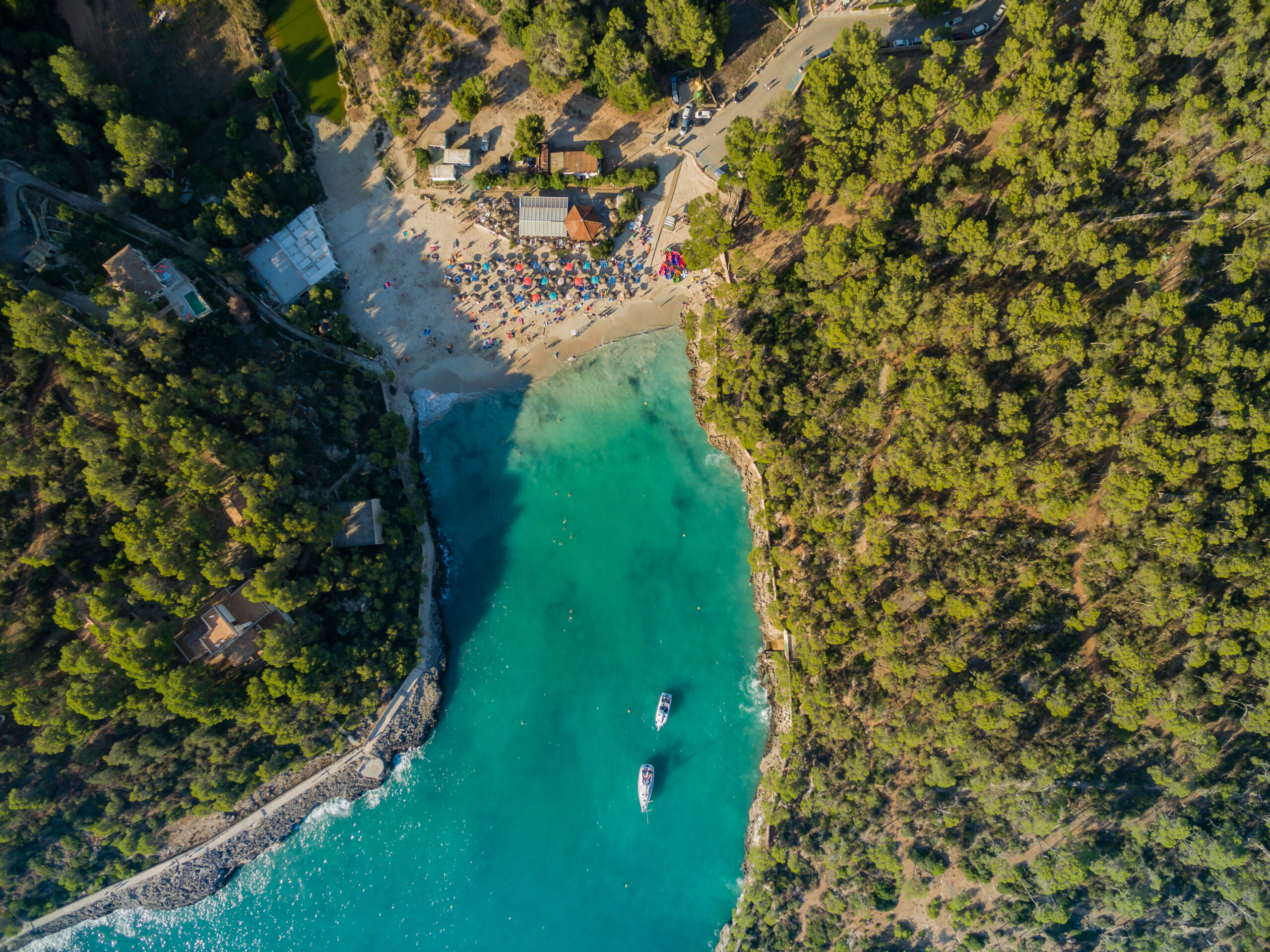 De mooiste stranden van Mallorca: top 10 per kust 4 Cala Mondrago recht van boven gezien, met turquoise water tussen beboste oevers, twee bootjes voor anker en het strand met parasols aan de kop van de baai