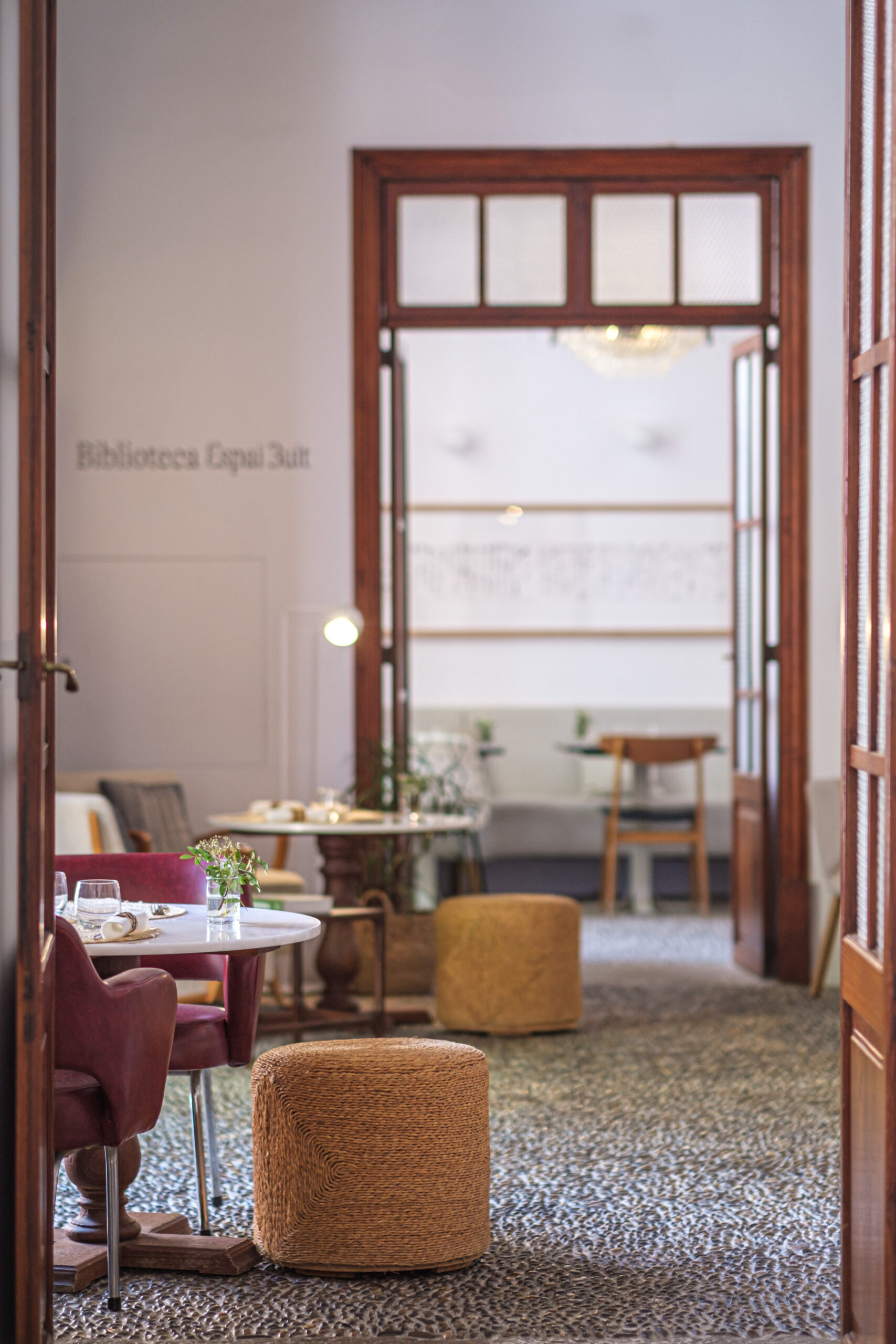 Mouna Palma: 100% biologisch vegetarisch eten in een oud casal 3 Doorkijk vanuit de eetzaal van Mouna naar de bibliotheek van Espai Buit, met lage fauteuils, poefs en een kiezelmozaïekvloer