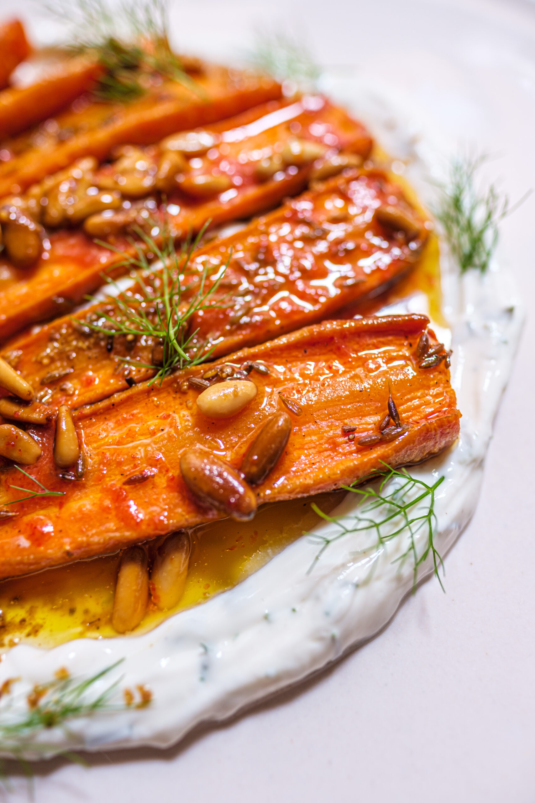 Mouna Palma: 100% biologisch vegetarisch eten in een oud casal 5 Geroosterde wortels met pijnboompitten, venkelgroen en een laag yoghurt op een wit bord