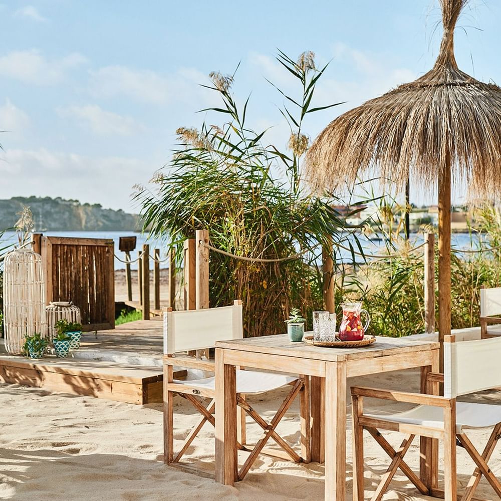 Nobu Hotel Ibiza Bay: het strandhotel van Talamanca 5 Tafels onder een rieten parasol bij strandrestaurant Chambao