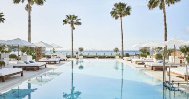 Het zwembad van Nobu Hotel Ibiza Bay met palmen en ligbedden aan de baai van Talamanca