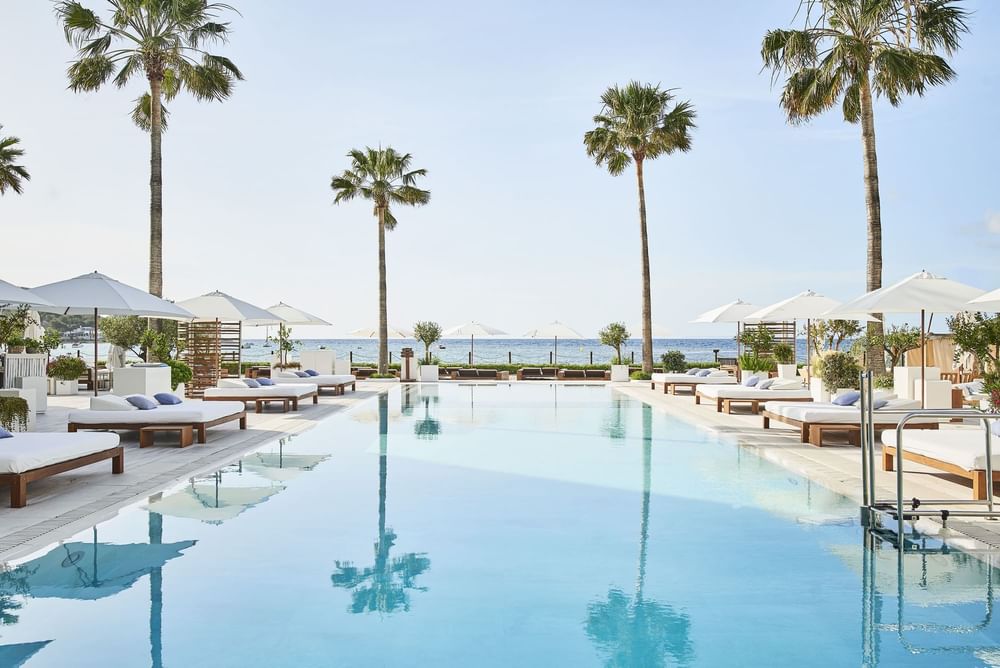 Nobu Hotel Ibiza Bay: het strandhotel van Talamanca 1 Het zwembad van Nobu Hotel Ibiza Bay met palmen en ligbedden aan de baai van Talamanca