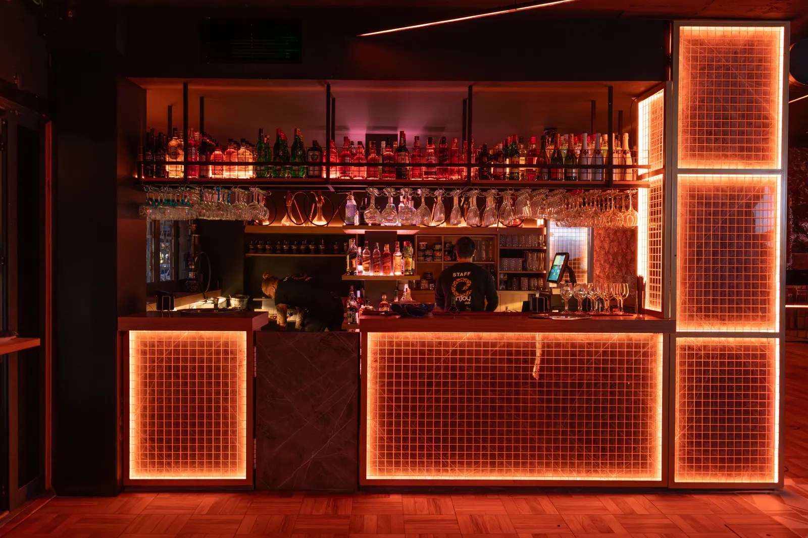 Outxide Club Alcúdia: de club van Noord-Mallorca 3 De bar van Outxide Club met flessenwand en oranje verlichte kaders