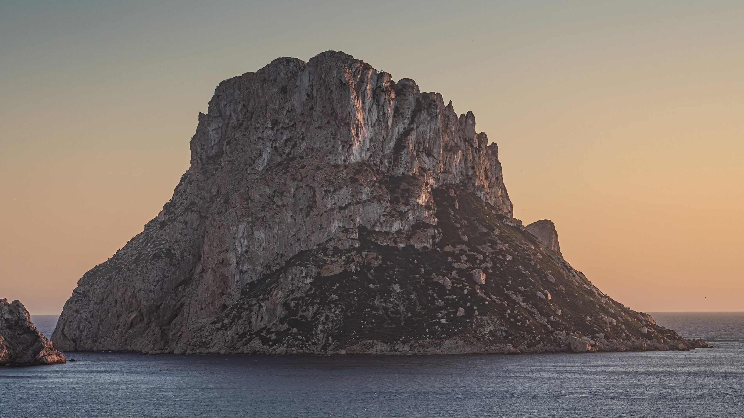 Partyboot Ibiza: prijzen, open bar, havens en de eerlijke nadelen 6 Es Vedrà bij zonsondergang met oranje lucht boven de zee bij Ibiza