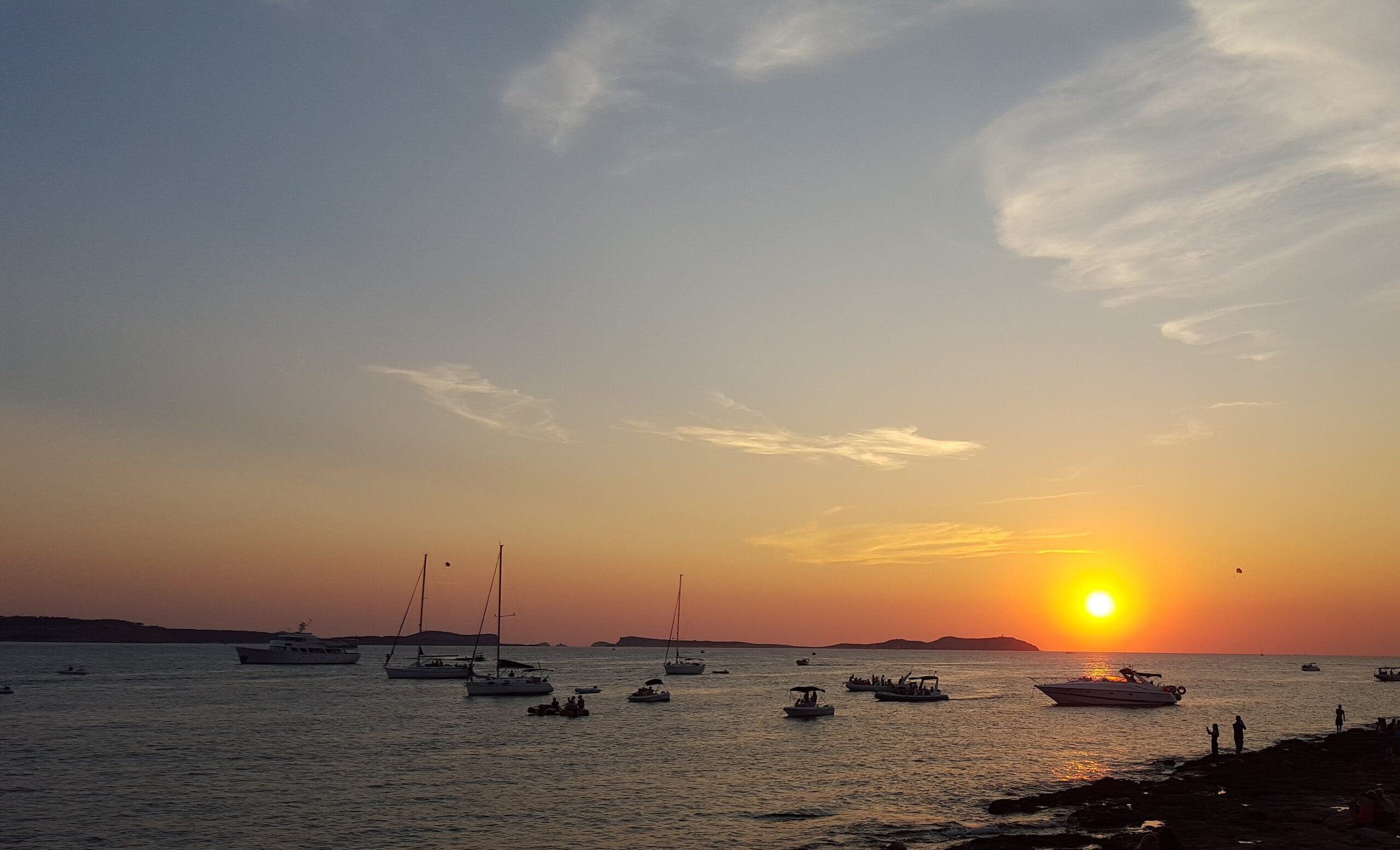 Partyboot Ibiza: prijzen, open bar, havens en de eerlijke nadelen 1 Zonsondergang bij Sant Antoni op Ibiza met excursieboten en een boot vol passagiers voor de kust