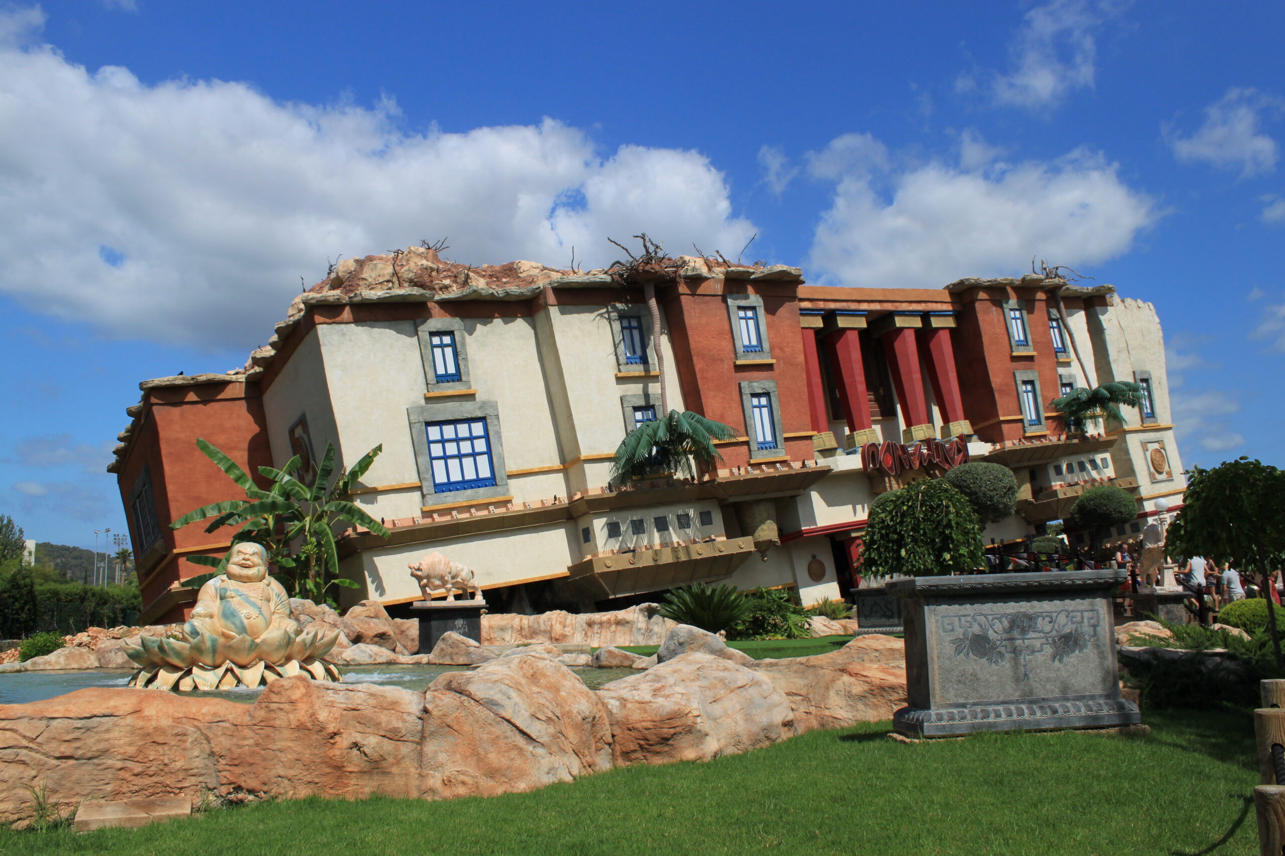 Het op zijn kop staande huis van het Katmandu Park in Magaluf, met de rotspartij en het groen ervoor