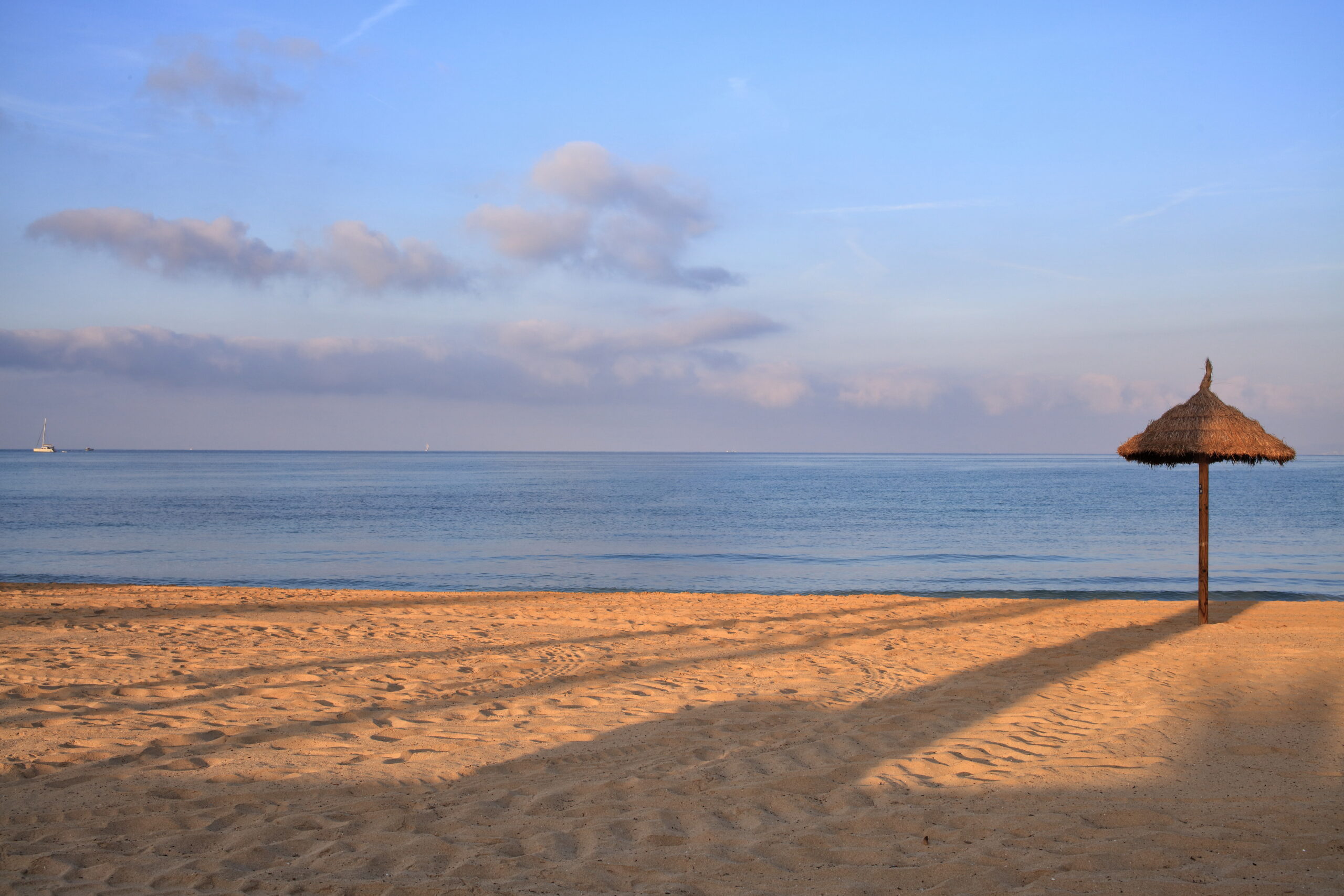 Playa de Palma (Mallorca): het grote stadsstrand bij Palma 5 Het lege strand bij balneario 1 aan de kant van s'Arenal in het vroege ochtendlicht, met een enkele rieten parasol op het gladgetrokken zand