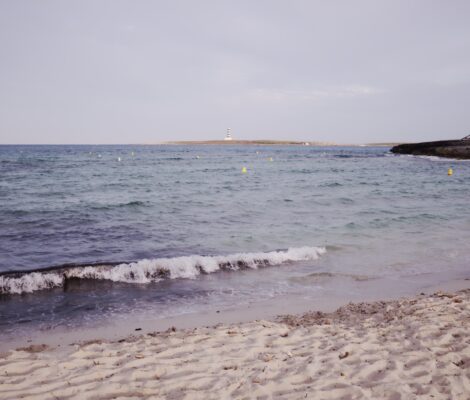 Punta Prima Menorca: het strand met de vuurtoren van Illa de l'Aire 3 Het witte zand van Punta Prima op Menorca met het eilandje Illa de l'Aire en zijn gestreepte vuurtoren aan de horizon