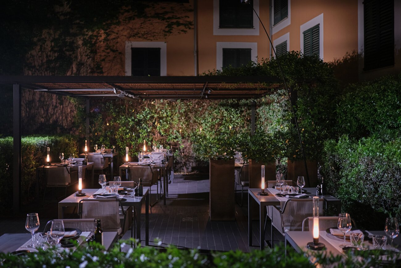 Quadrat in Palma: eten in de tuin van Hotel Sant Francesc 1 De tuin van restaurant Quadrat in Palma bij avond, met gedekte tafels onder een pergola en kaarslicht tussen het groen