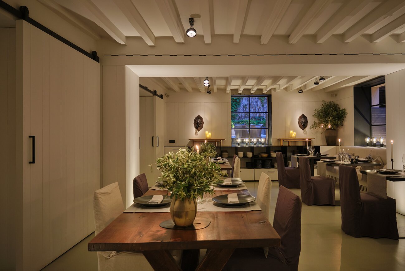 Quadrat in Palma: eten in de tuin van Hotel Sant Francesc 3 Lichte eetkamer van Quadrat in Palma met een balkenplafond, bruine stoelen en een gedekte tafel met bloemen