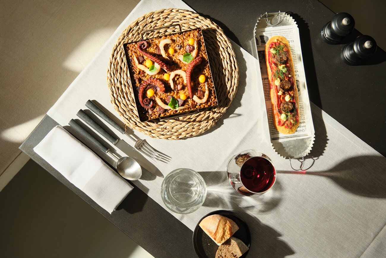Quadrat in Palma: eten in de tuin van Hotel Sant Francesc 5 Twee belegde coca's van Quadrat in Palma op een gedekte tafel, met bestek en een glas rode wijn