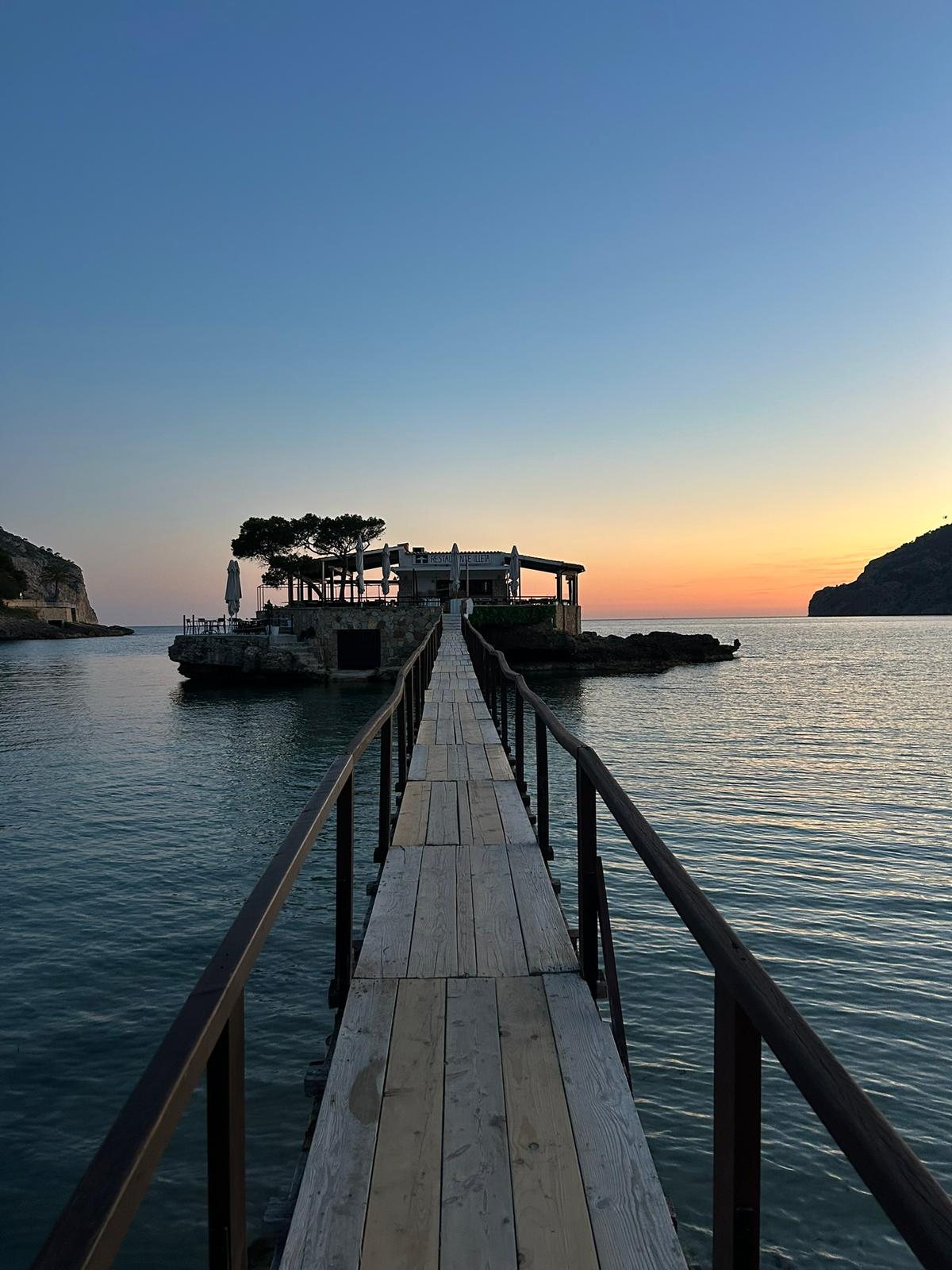Restaurante Illeta Mallorca: eten op een rotseilandje bij Camp de Mar 1 De houten loopbrug naar het rotseilandje met Restaurante Illeta bij Camp de Mar, in de schemering met de naam op de gevel