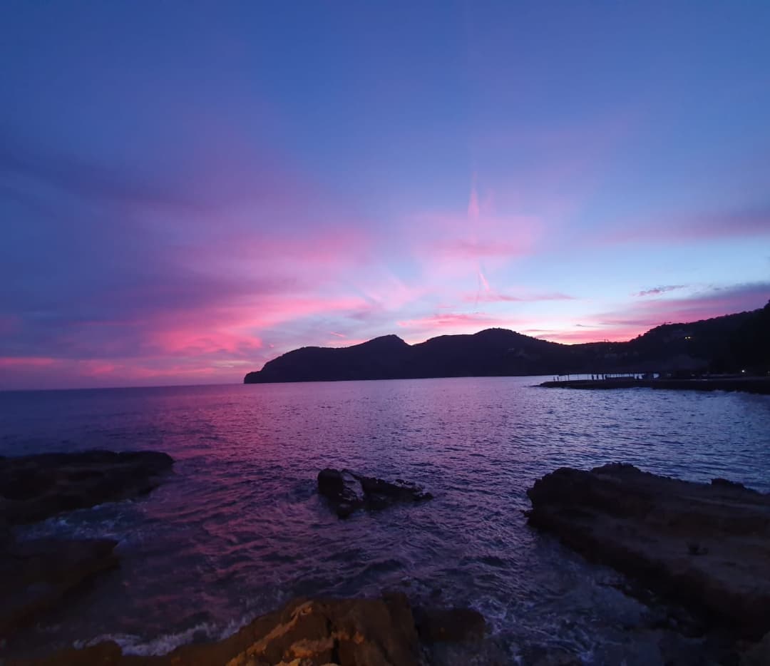 Restaurante Illeta Mallorca: eten op een rotseilandje bij Camp de Mar 6 Roze schemering boven de baai van Camp de Mar met de loopbrug naar het eilandje rechts in beeld