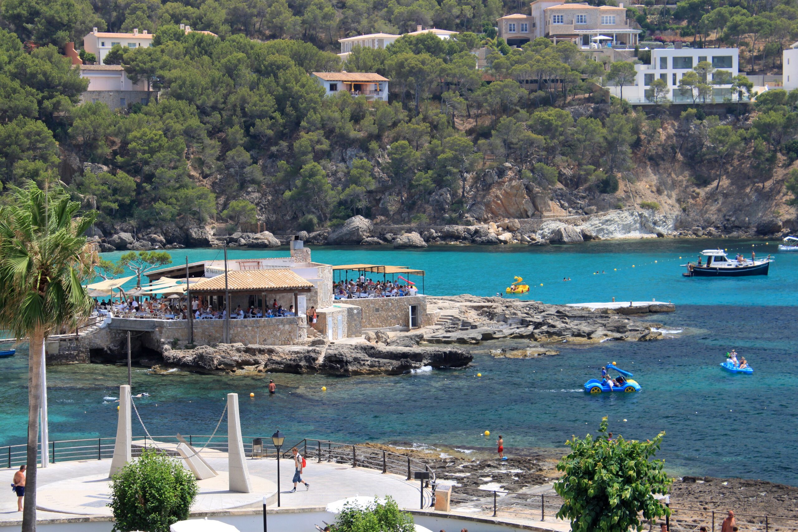 Restaurante Illeta Mallorca: eten op een rotseilandje bij Camp de Mar 2 Restaurante Illeta op het rotseilandje bij Camp de Mar in de zomer, met volle terrassen onder zonneschermen en turquoise water eromheen