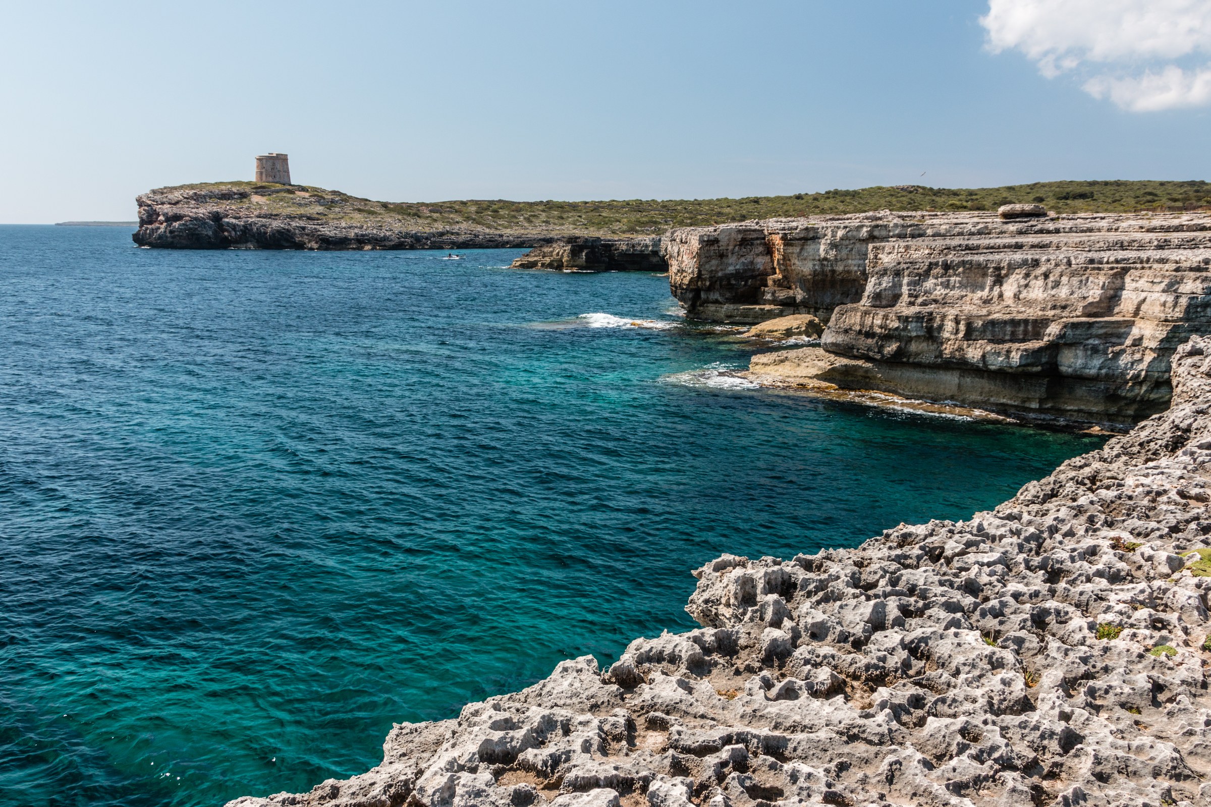 Vlakke kalkstenen rotsplaten en helder turquoise water aan de kust bij S'Algar in de zuidoosthoek van Menorca